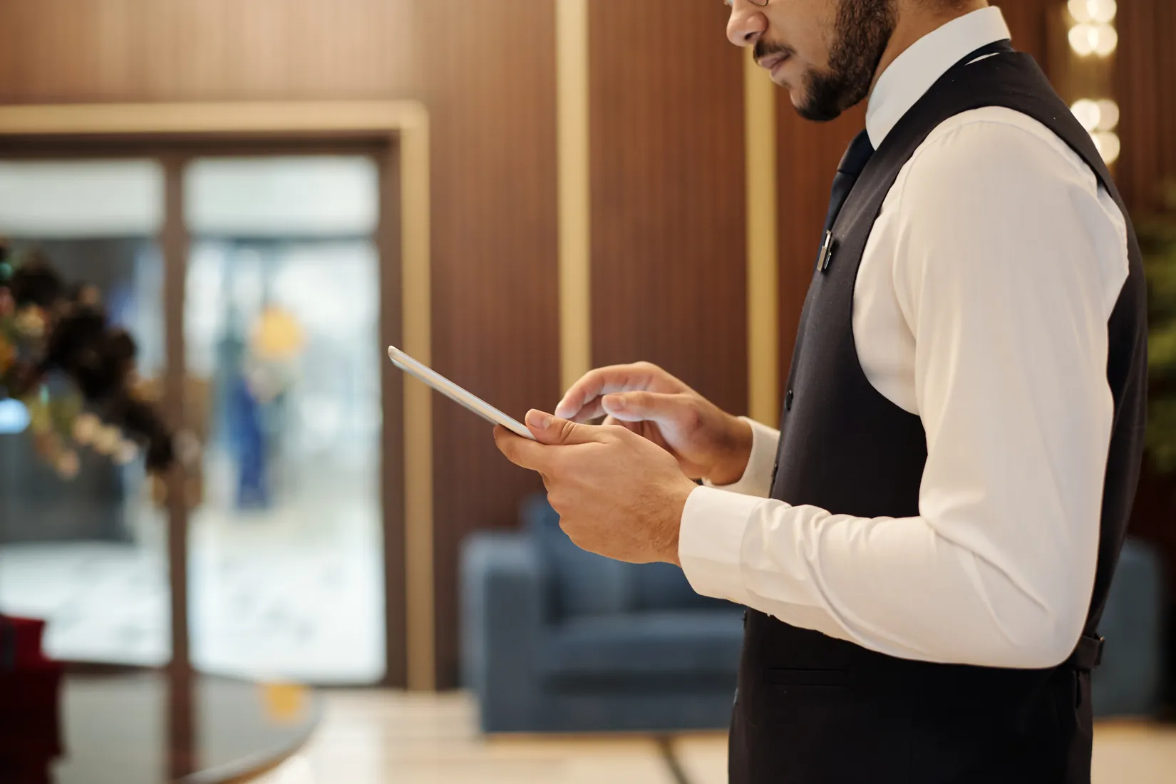 A crew member in uniform using a tablet in a guest lounge