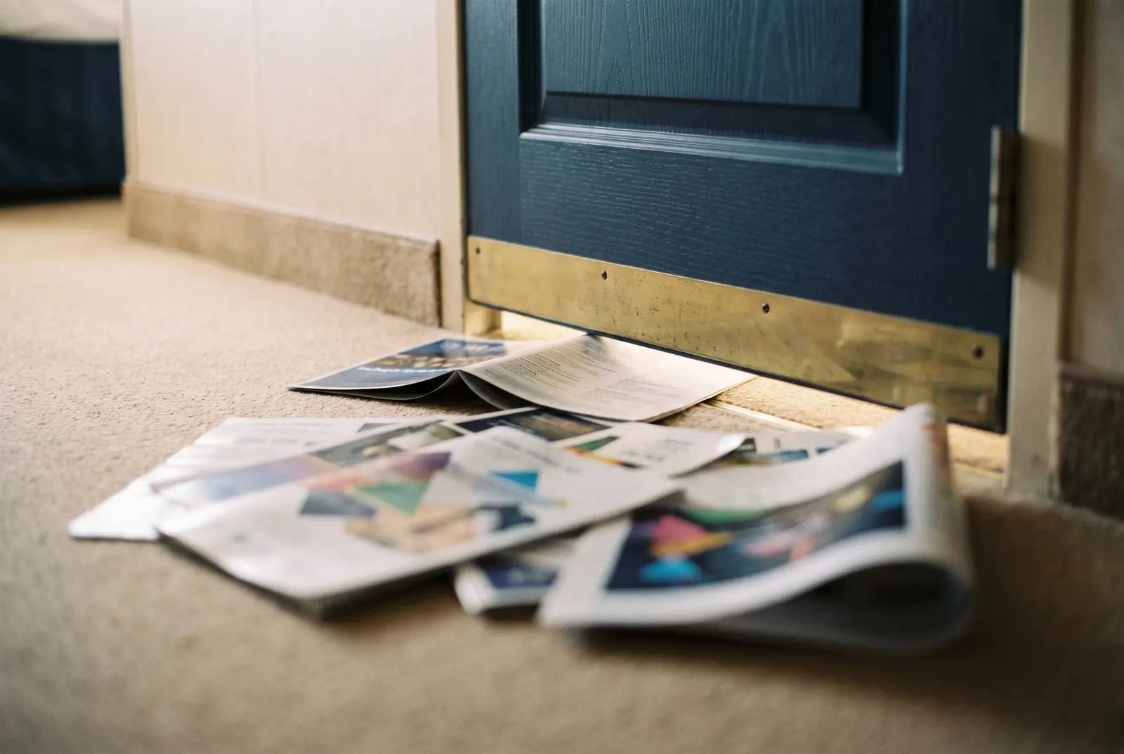 A pile of glossy promotional flyers slid under a cabin door onto the carpet